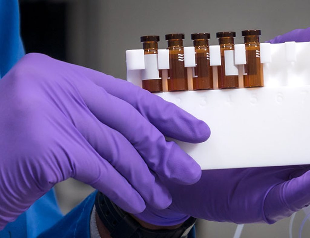 A close up of a chemist in lab holding Syrris Asia collector